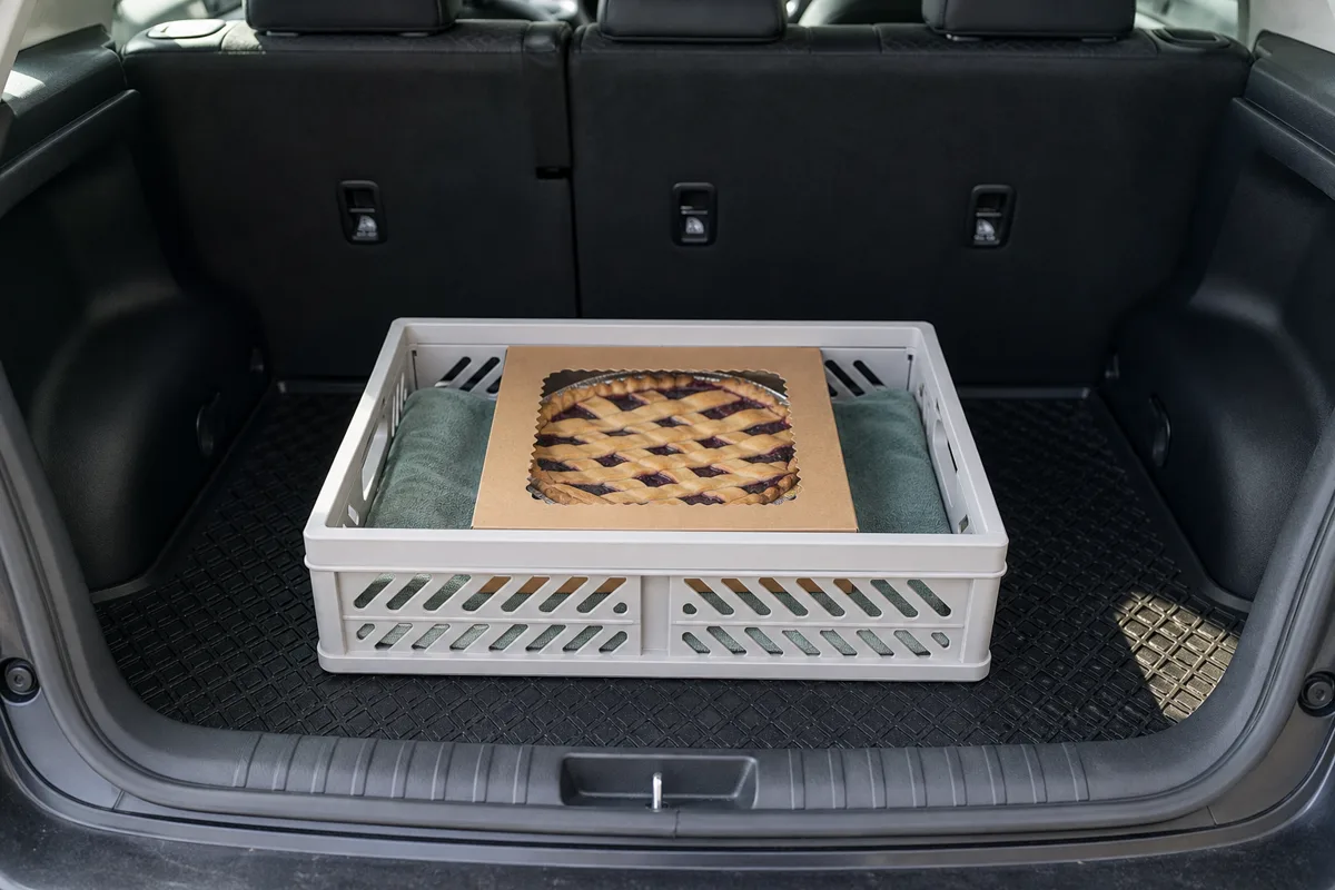 Boxed pie resting level on a nonslip mat in a clean vehicle cargo area, with no objects stacked on top